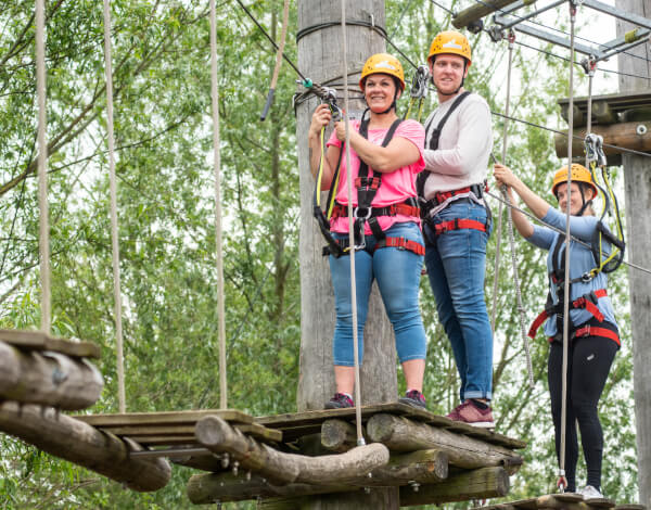 Anfahrt zum Kletterpark Drei Erwachsene klettern in der Anlage